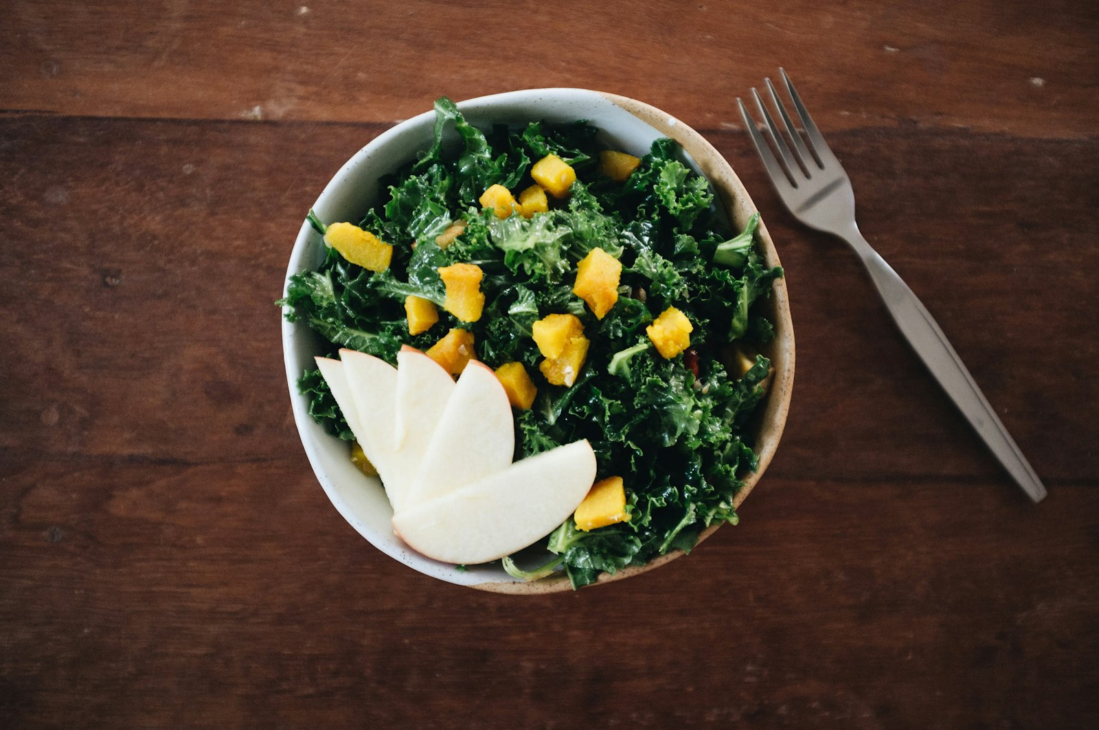 Kale salad with mango in a white bowl