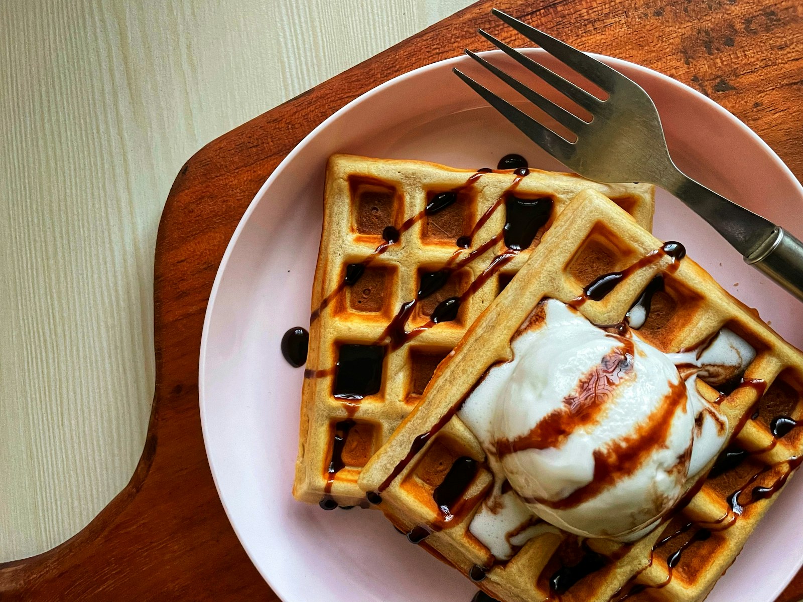 Belgian waffle with whipped cream on a wooden board