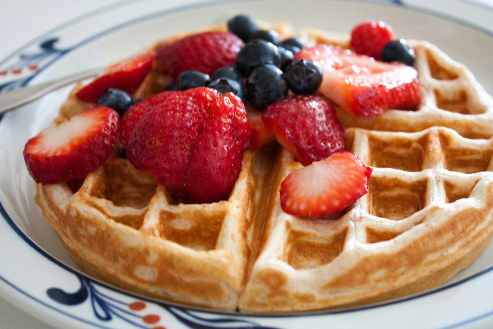 Waffle piled with strawberries and blueberries