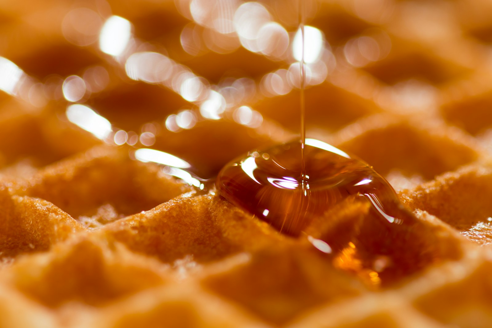 Maple syrup pouring over a golden waffle