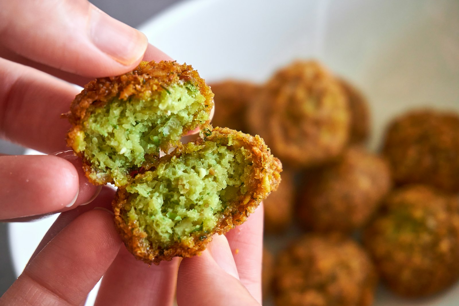 Crispy falafel broken open to show the green herb center