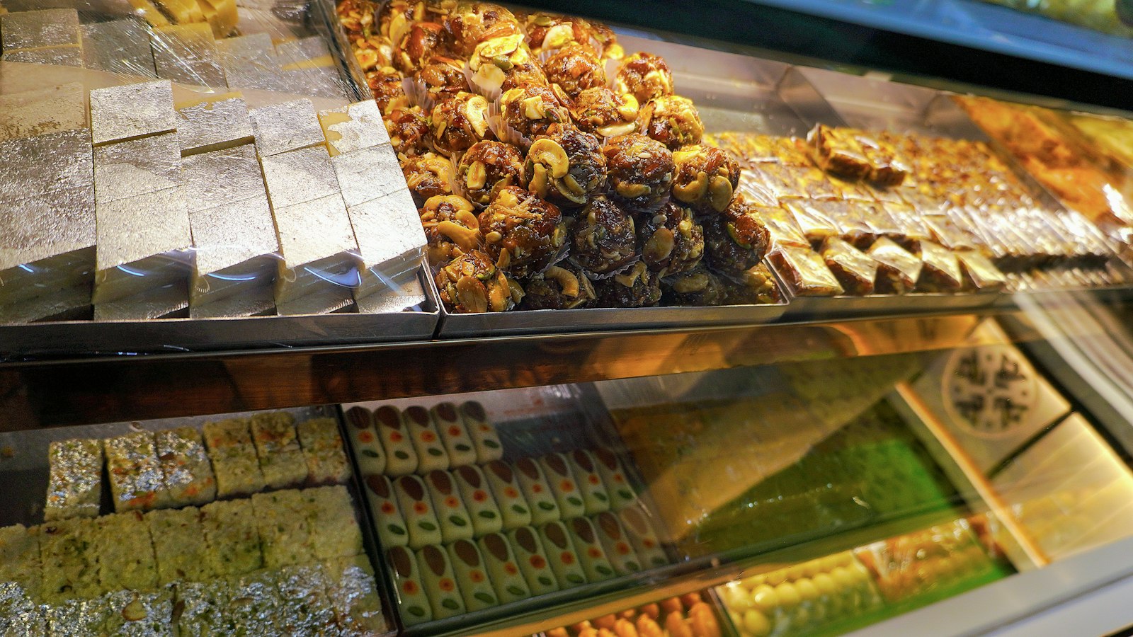 Trays of barfi and other sweets in a sweet shop window