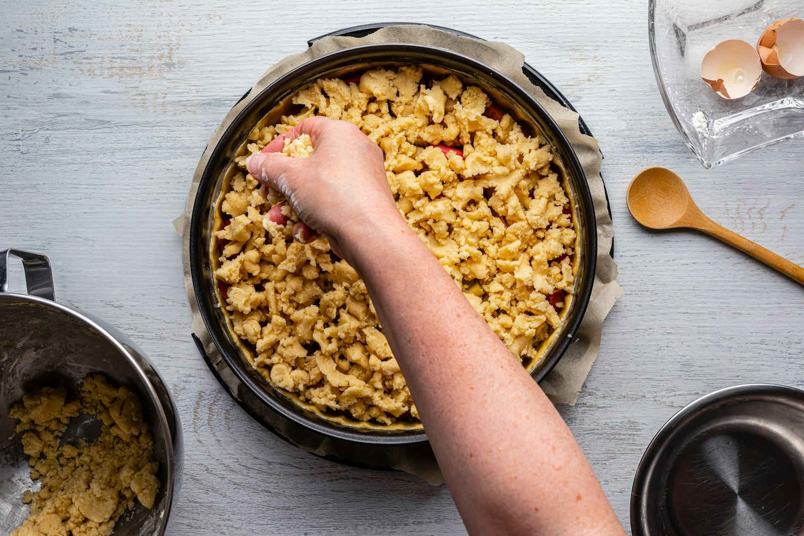Hand sprinkling crumble topping over fruit