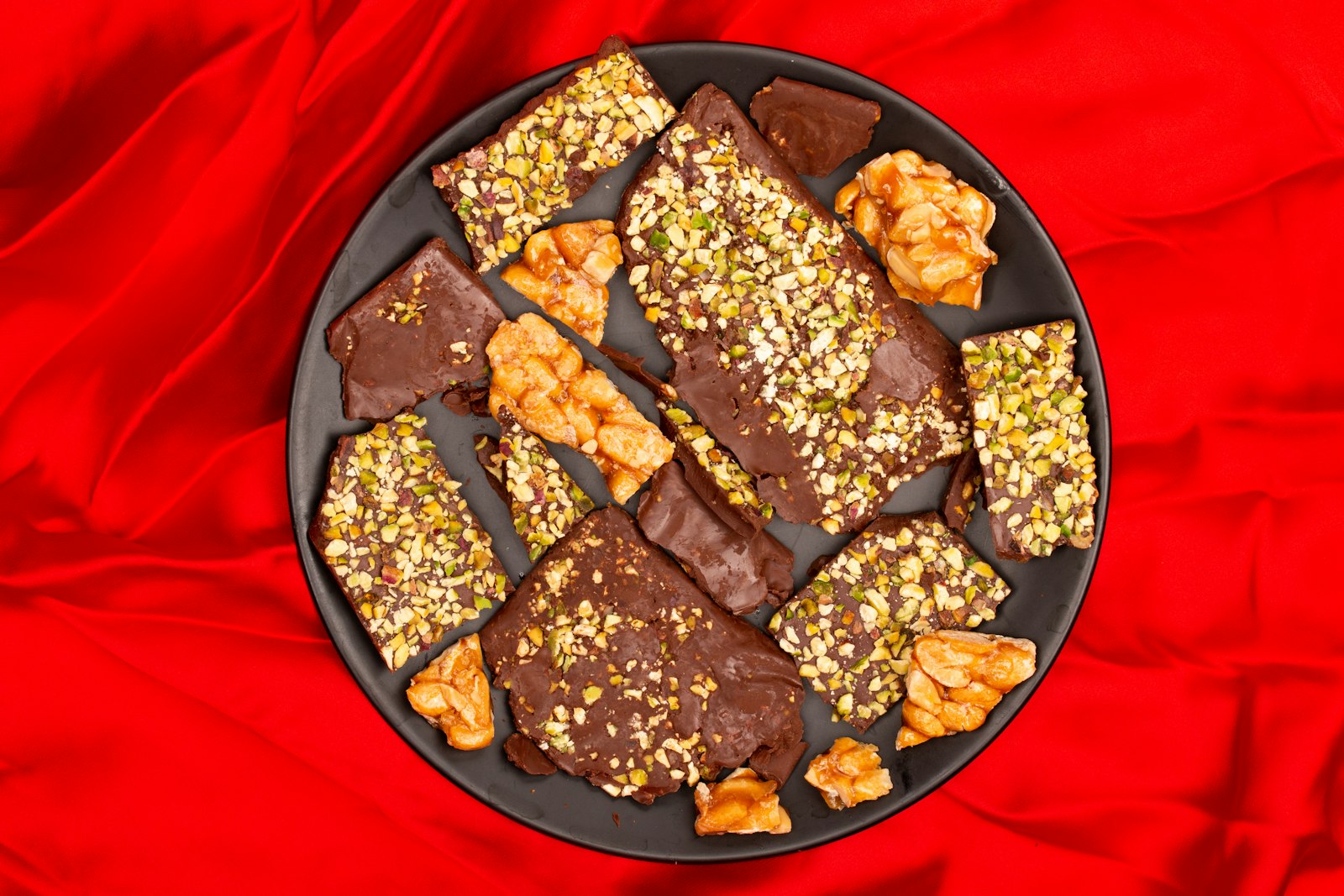 Christmas candy bark with nuts and dried fruit on a red plate
