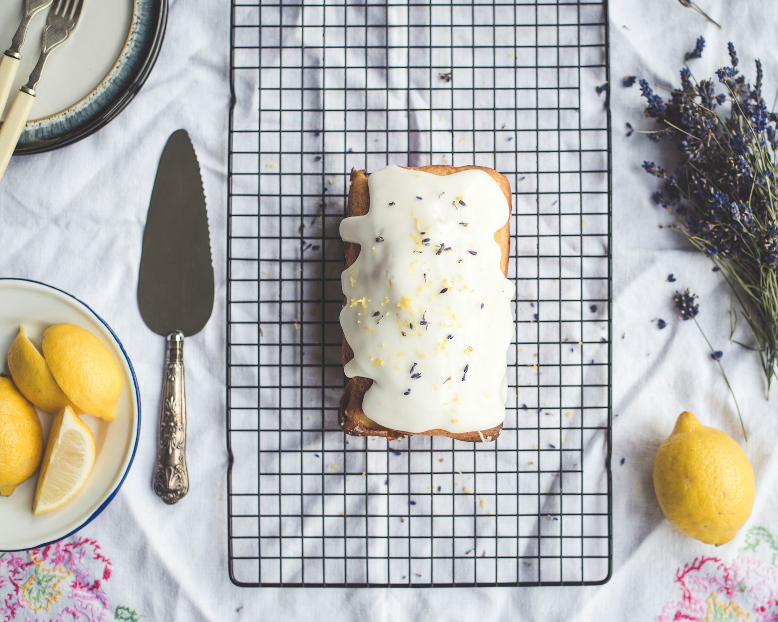 Lemon drizzle loaf cake with white glaze on a cooling rack