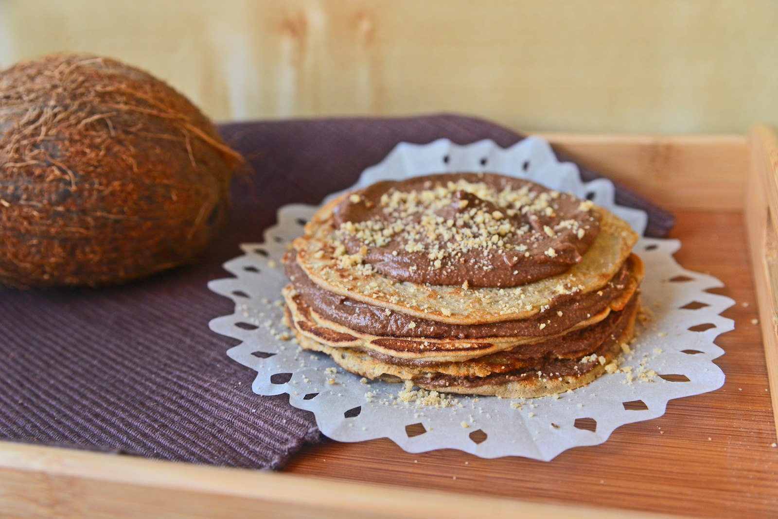 Stack of thin pancakes layered with chocolate spread and nuts