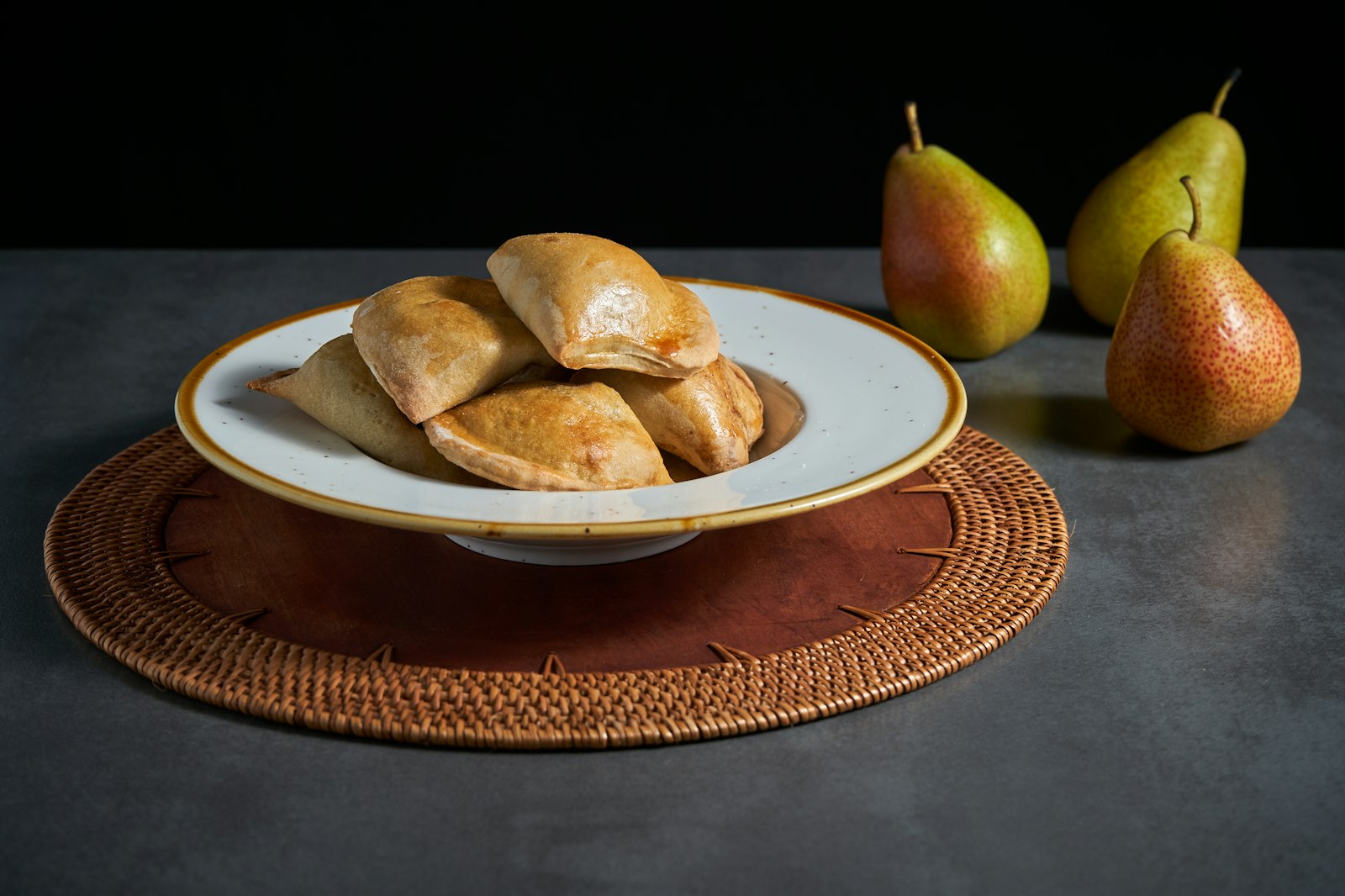 Pear puff pastry pockets in a bowl with fresh pears