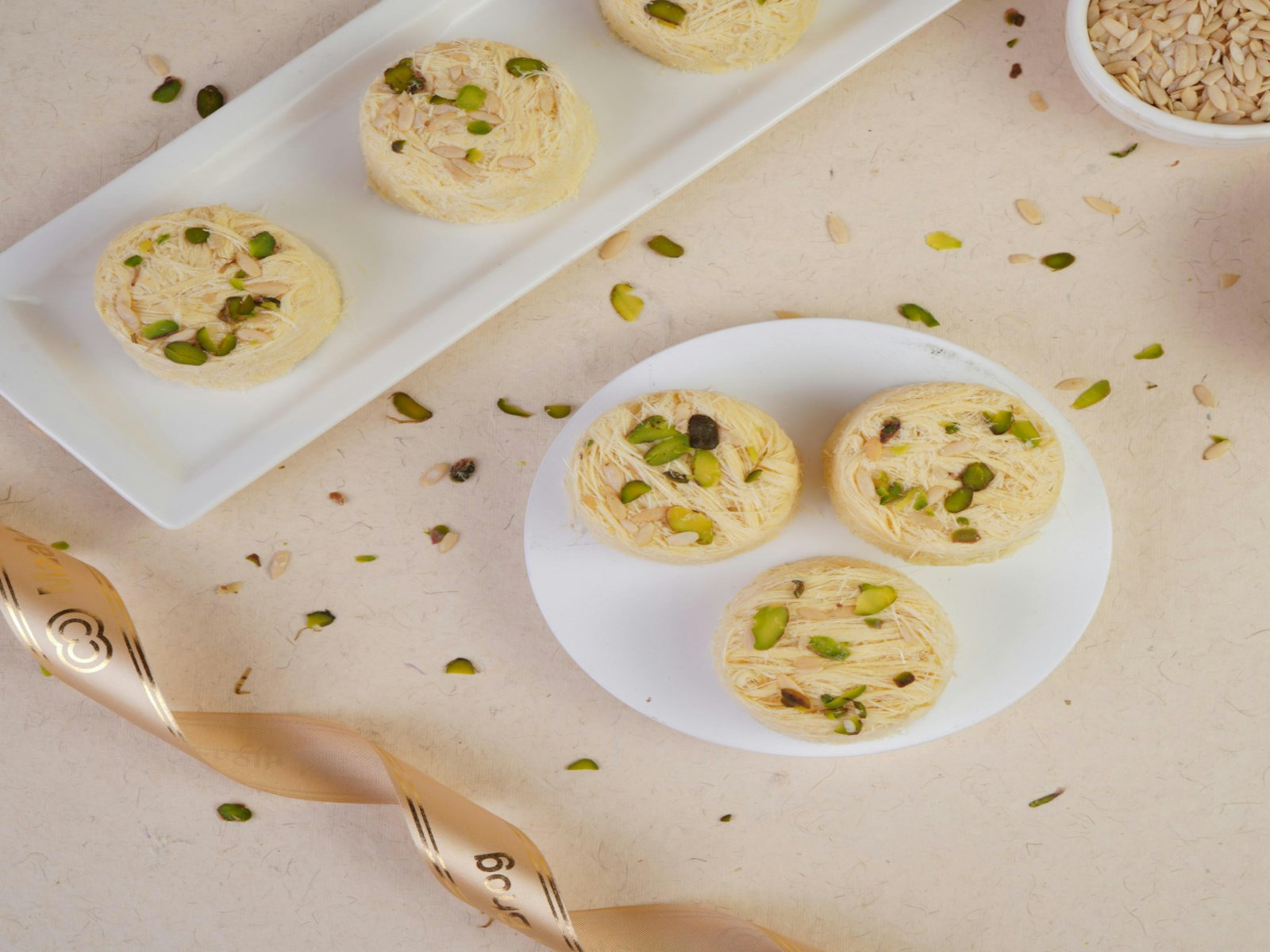 Rasmalai topped with chopped pistachios on a white plate
