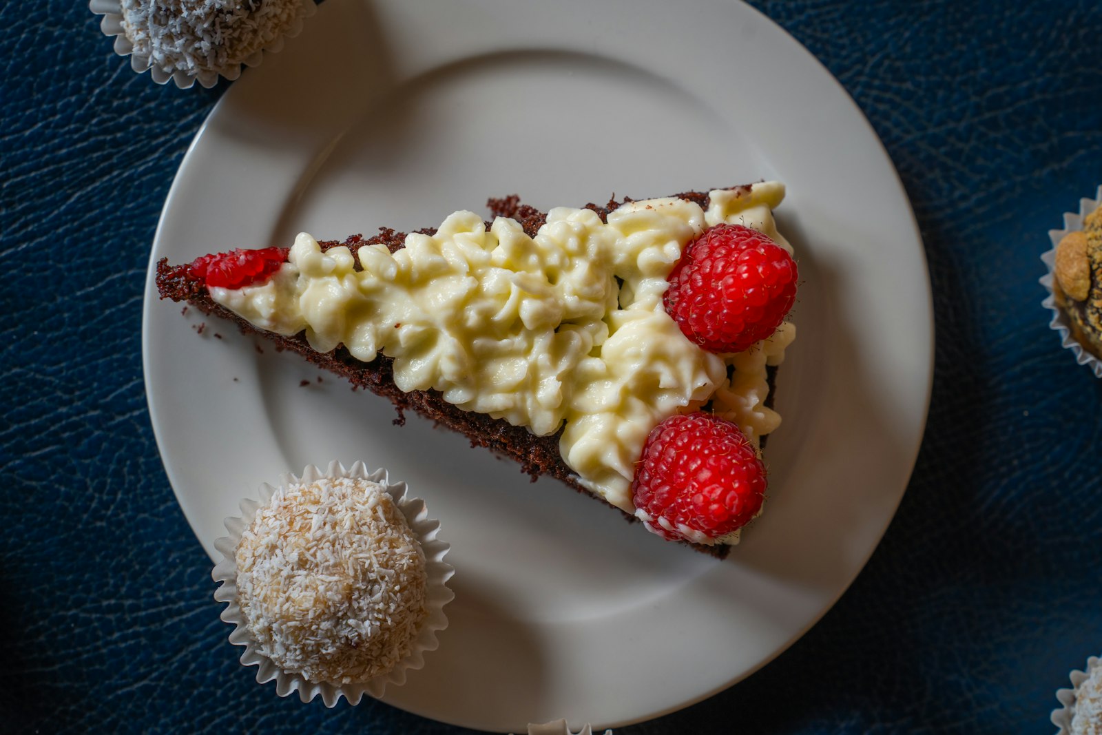 Chocolate cake slice topped with cream and raspberries