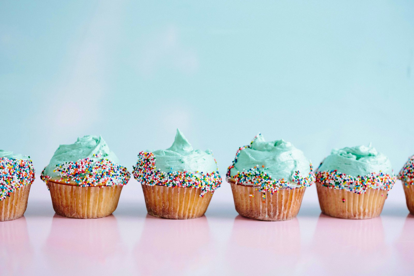 Row of vanilla cakes with mint frosting and sprinkles