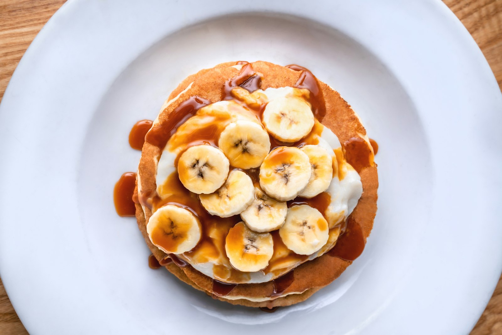Stack of pancakes topped with fruit slices and caramel