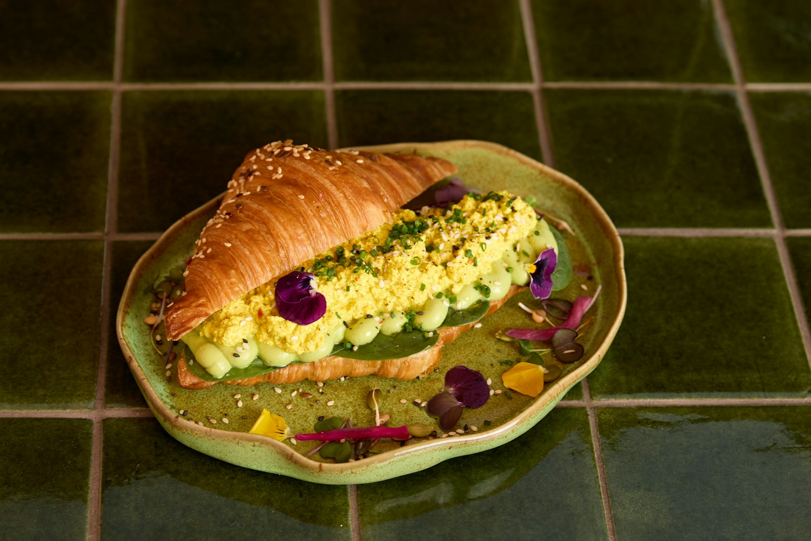 Croissant filled with creamy eggs on a green plate