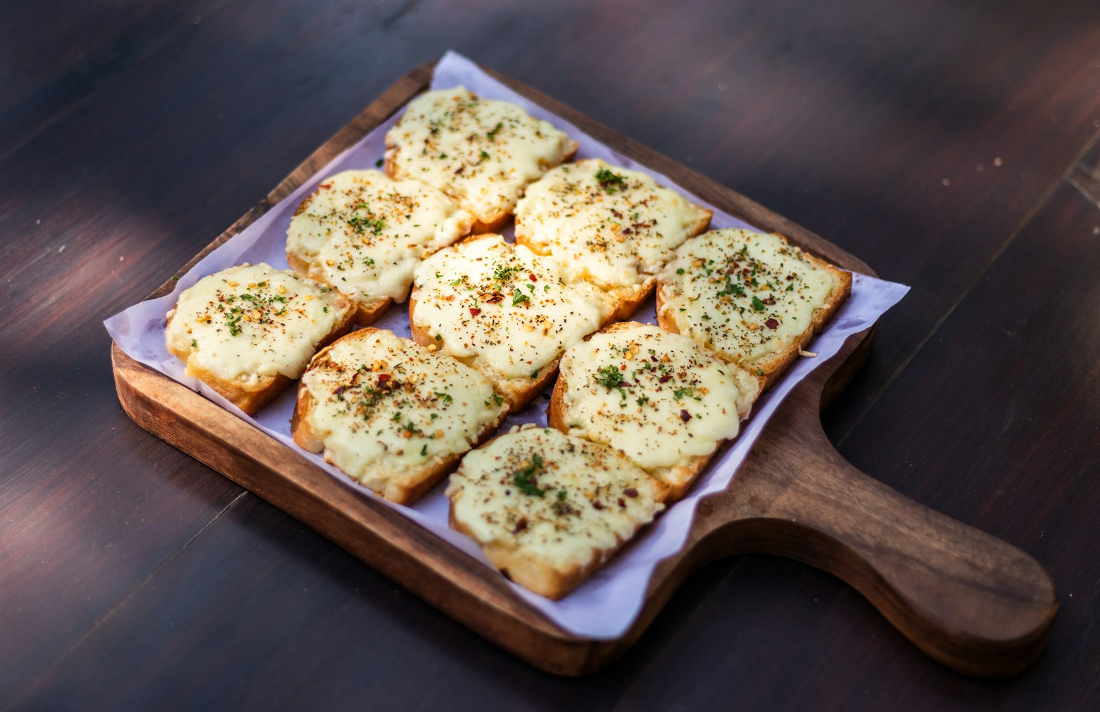 Cheesy garlic bread slices on a wooden board