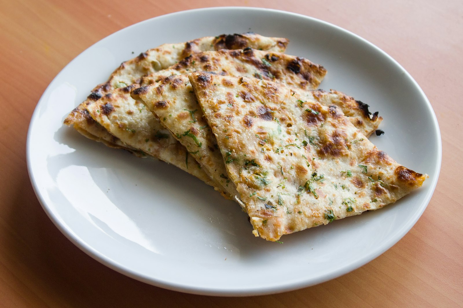 Garlic naan with herbs on a white plate