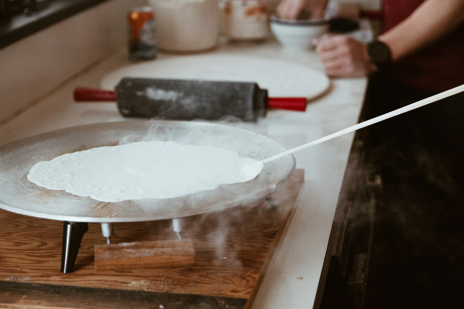 Lefse flatbread being turned on a round griddle