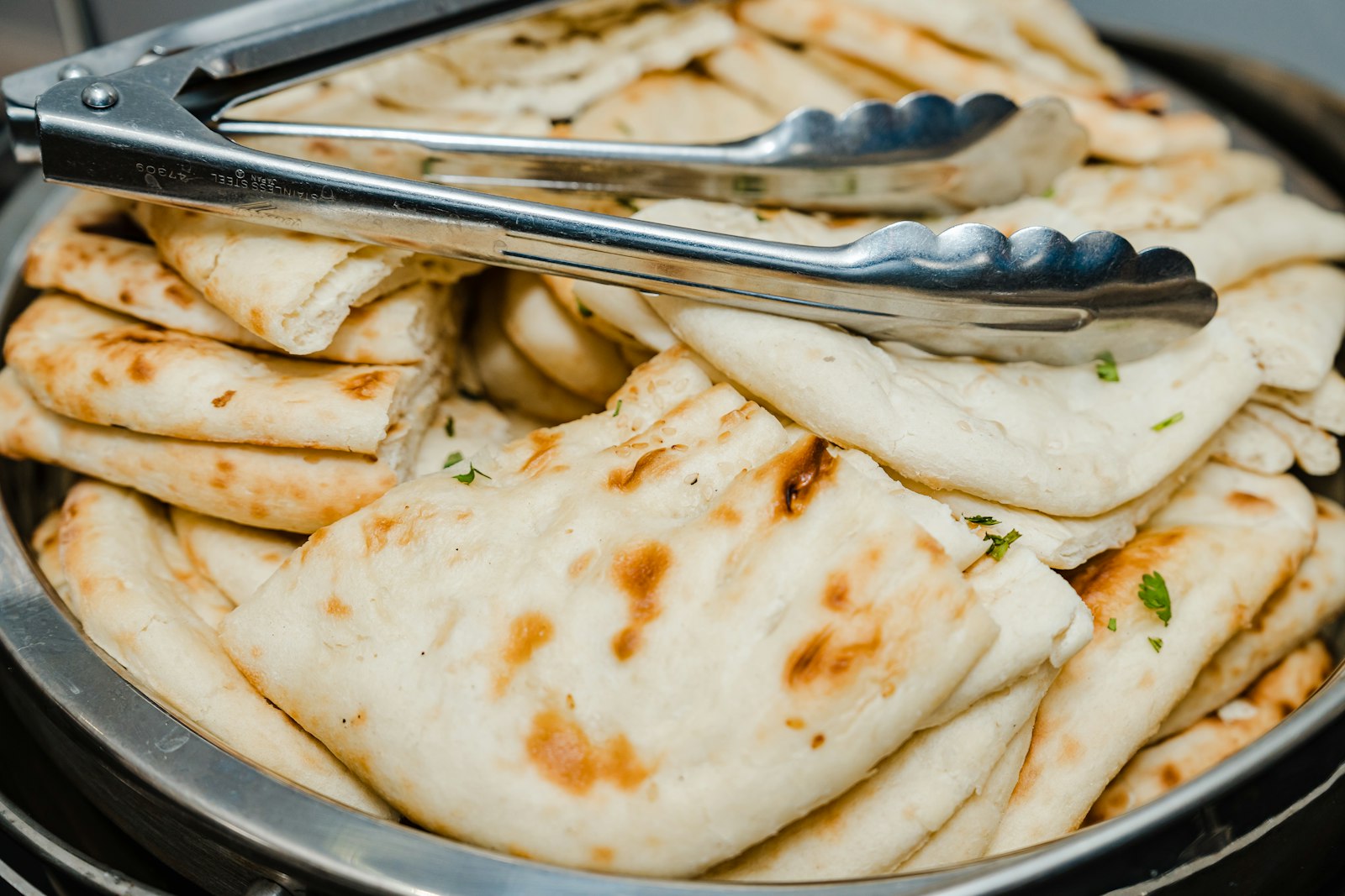 Soft homemade naan flatbread piled on a plate