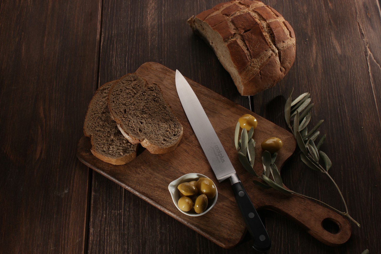 Olive studded loaf sliced with a bowl of olives