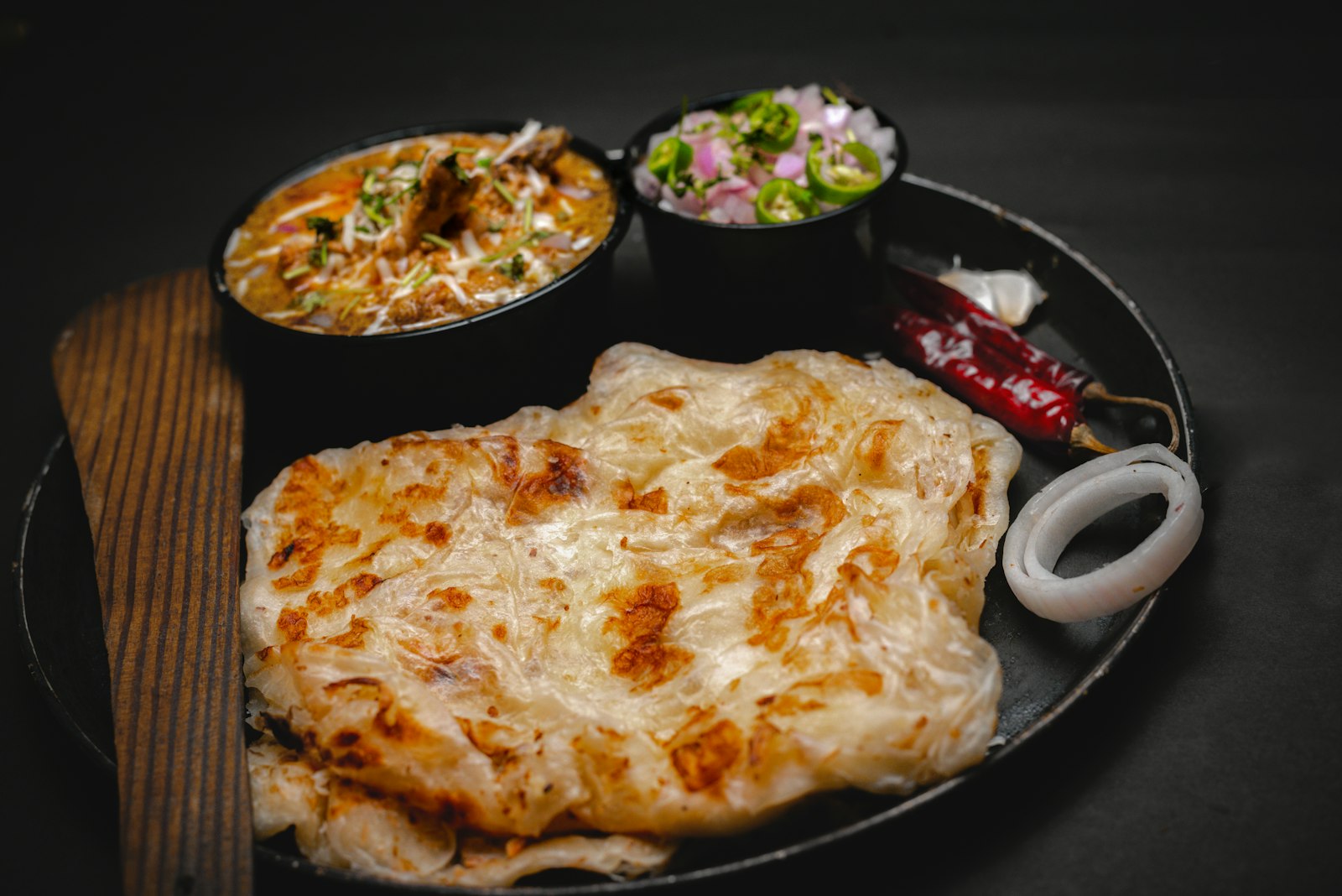 Flaky paratha flatbread served with curries and salad