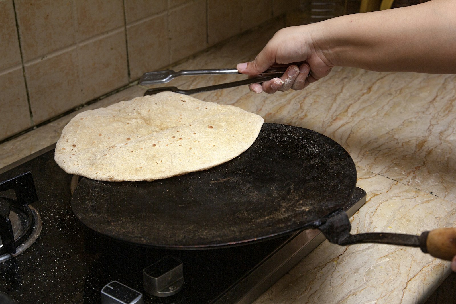 Roti being cooked on a hot iron griddle