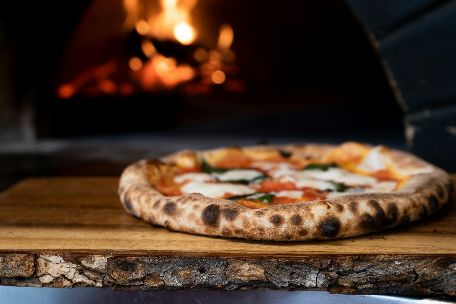 Blistered pizza crust in front of a wood fired oven