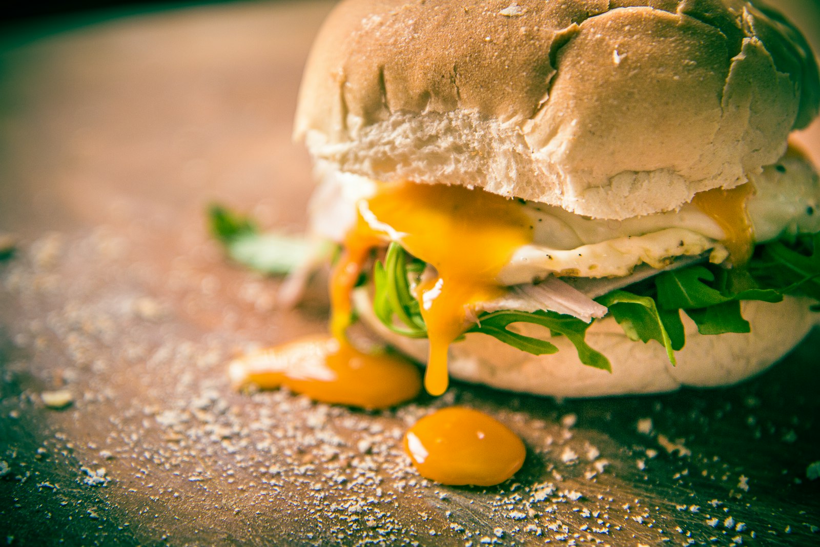 Fried egg sandwich with yolk dripping from a soft bun