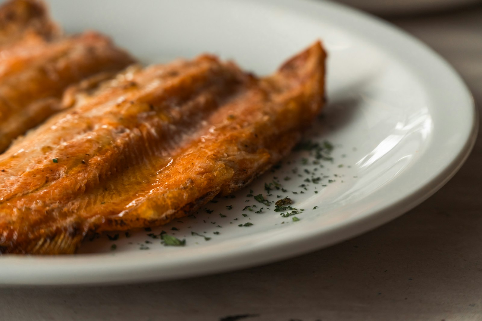 golden cornmeal fried fish fillet on a white plate