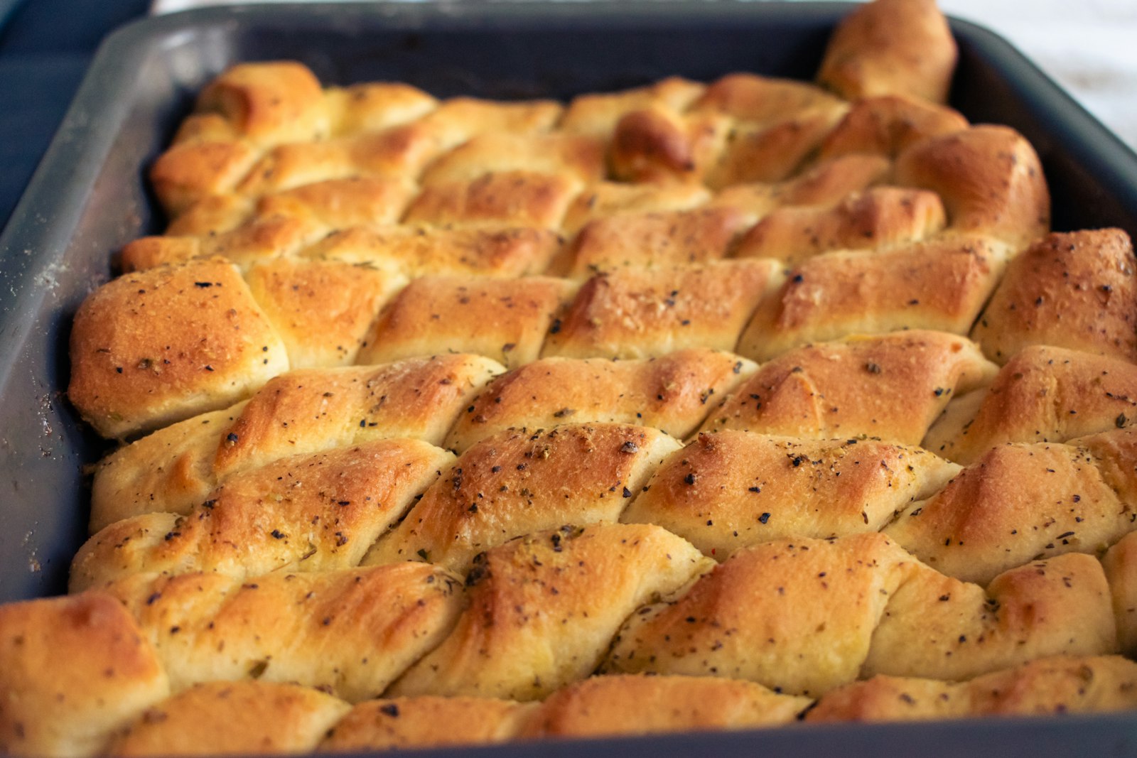 Homemade dinner rolls: golden garlic knots in a baking pan