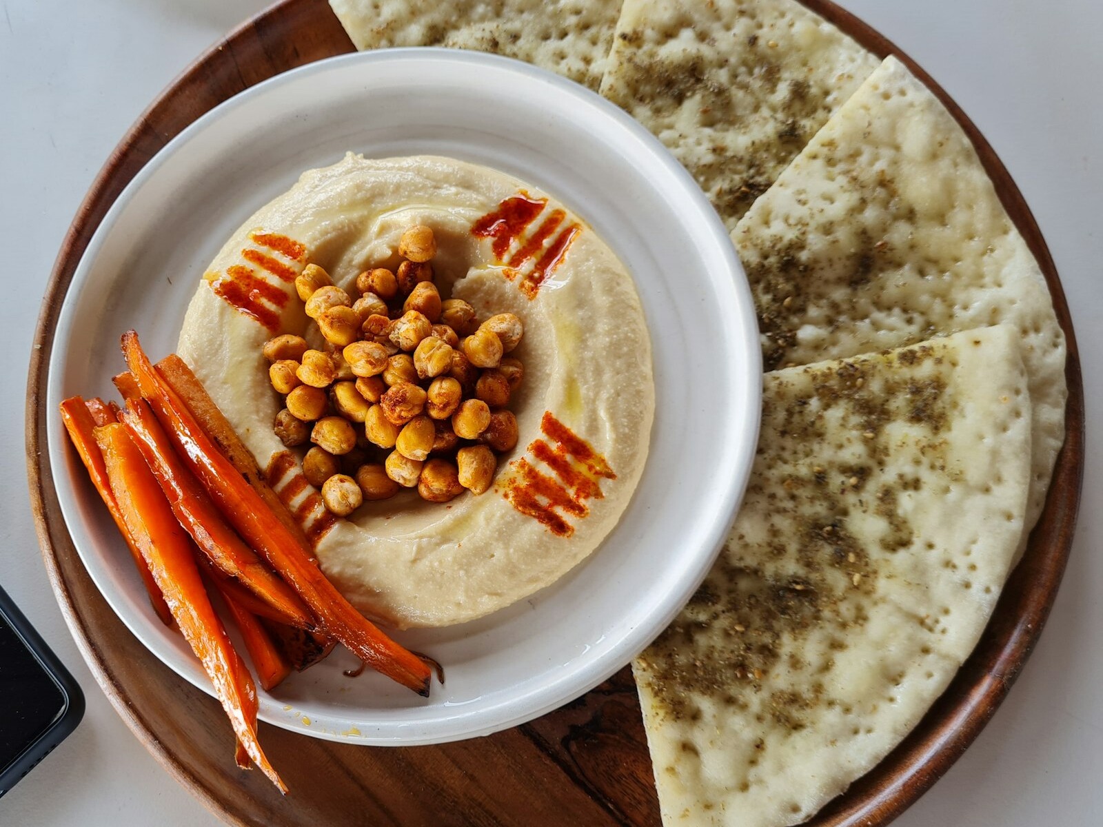 Hummus topped with chickpeas next to carrot sticks