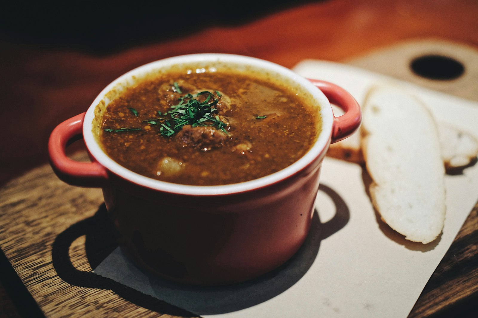 Slow cooker dinners: hearty lentil soup in a red cast iron pot on a wooden table