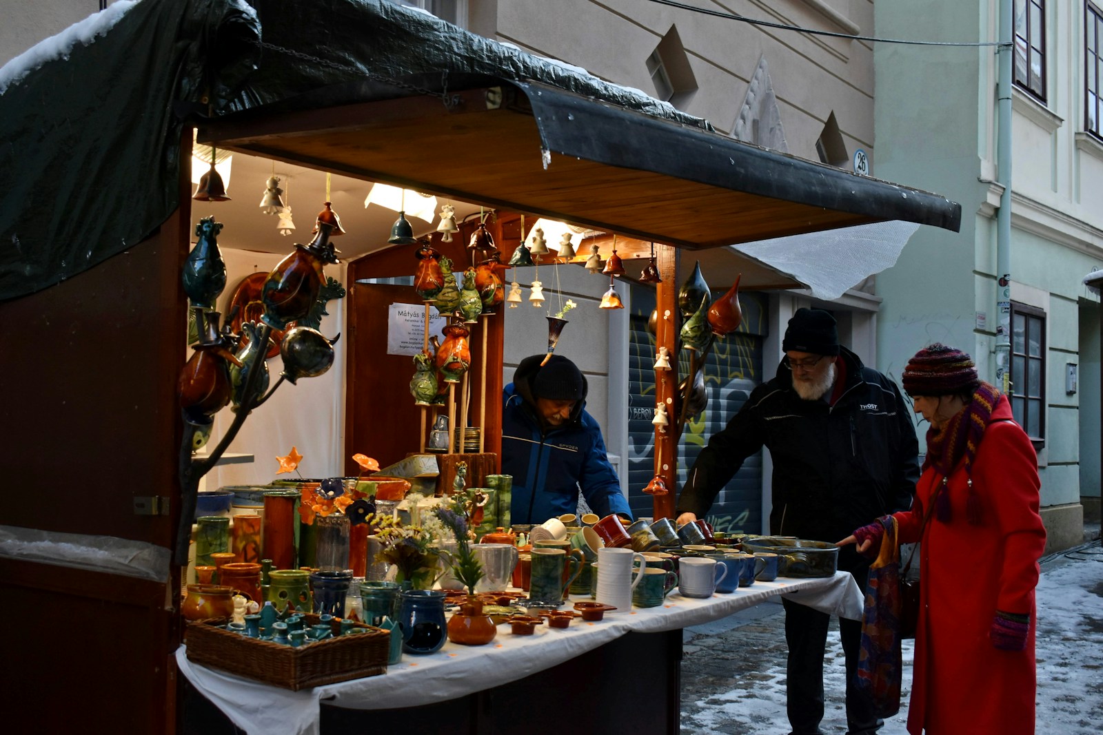 Holiday market stall with handmade crafts and shoppers in winter coats