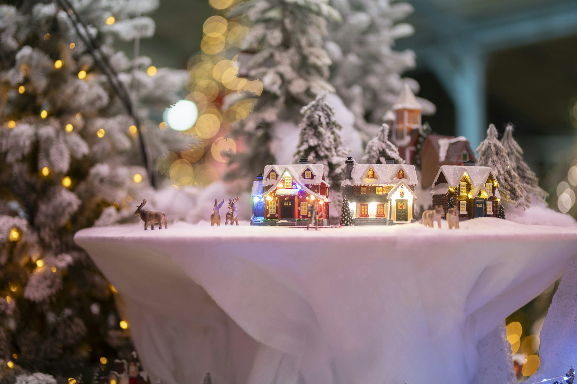 Christmas Bar Cart Ideas with a snowy miniature village of lit houses and tiny reindeer