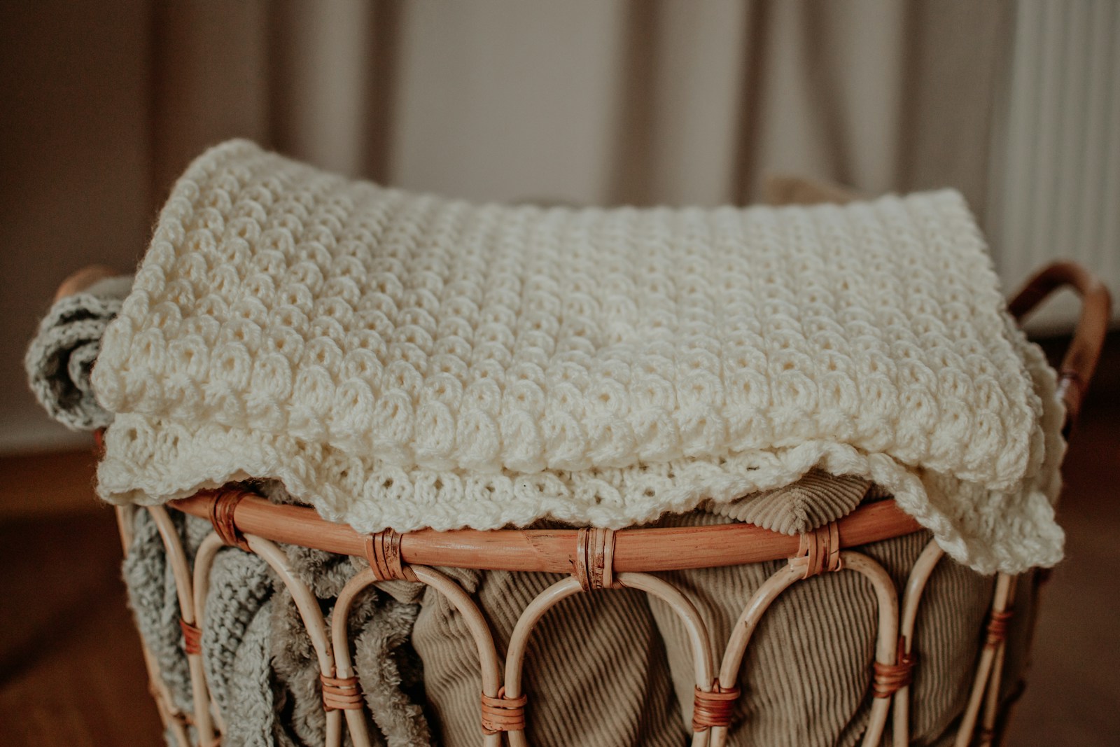 Knit blanket folded over a woven hamper