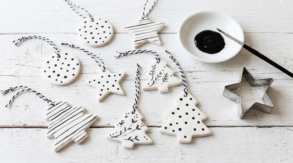 Black and white Christmas decor clay ornaments painted with polka dots and stripes on a white table
