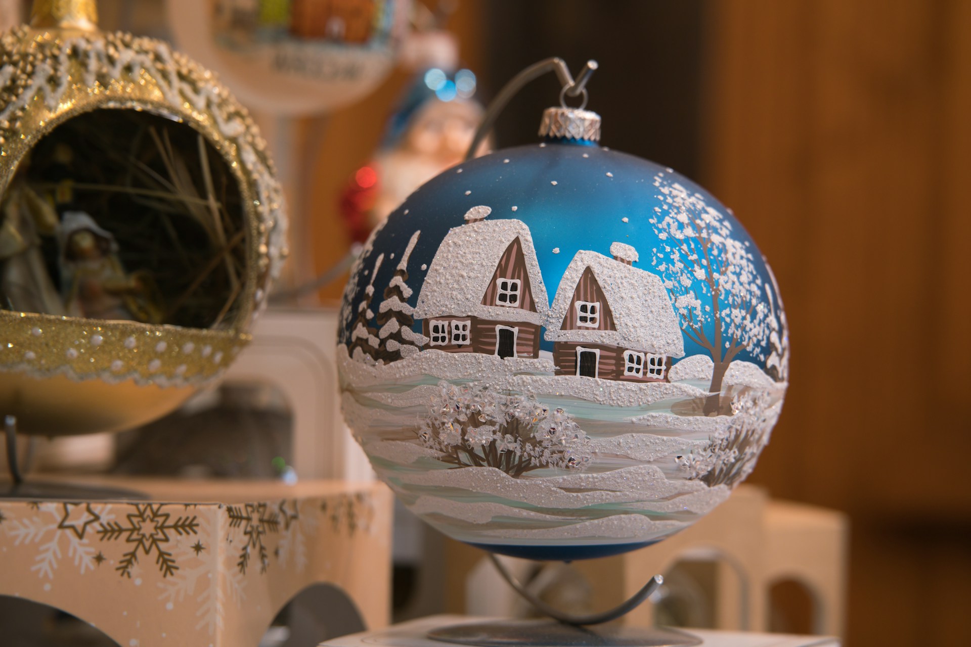 Blue glass ball with snowy white cottages and a frosted tree