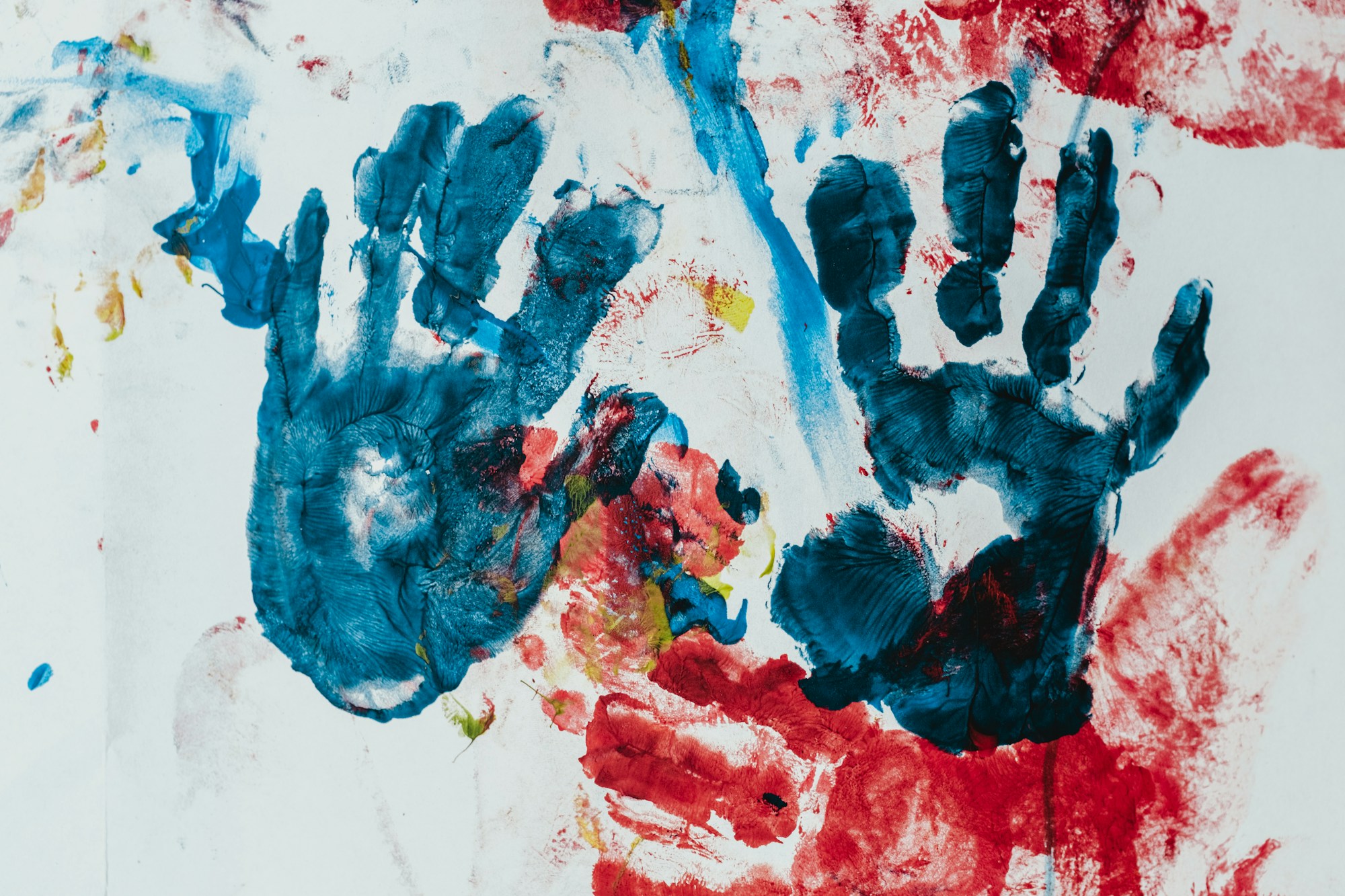 Blue and red handprints of different sizes painted on white paper