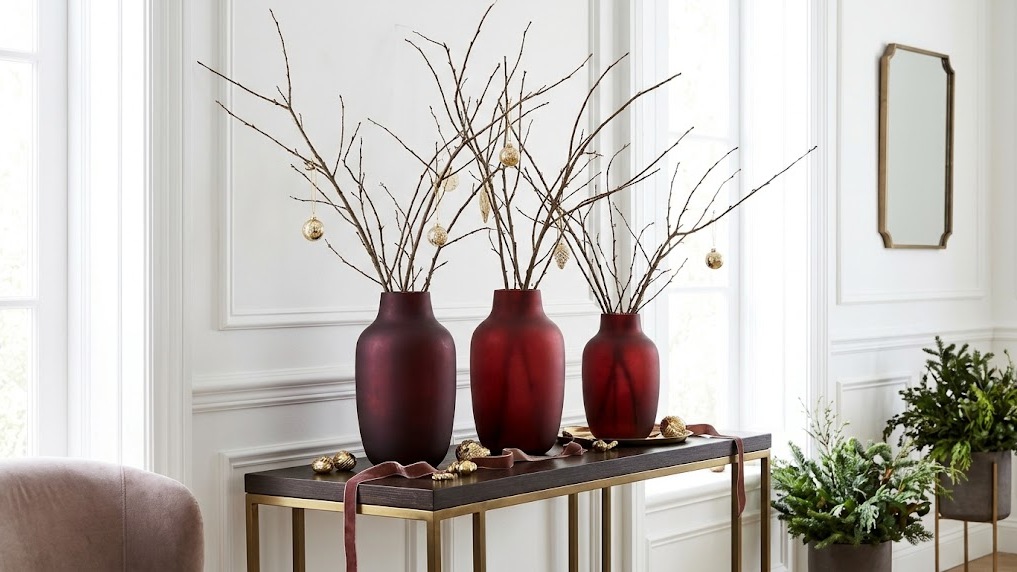 Burgundy painted vases with bare branches on a console table