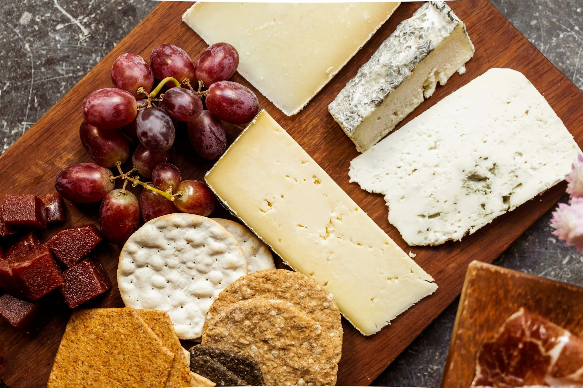 Wooden board with crackers, grapes and soft cheese wedges