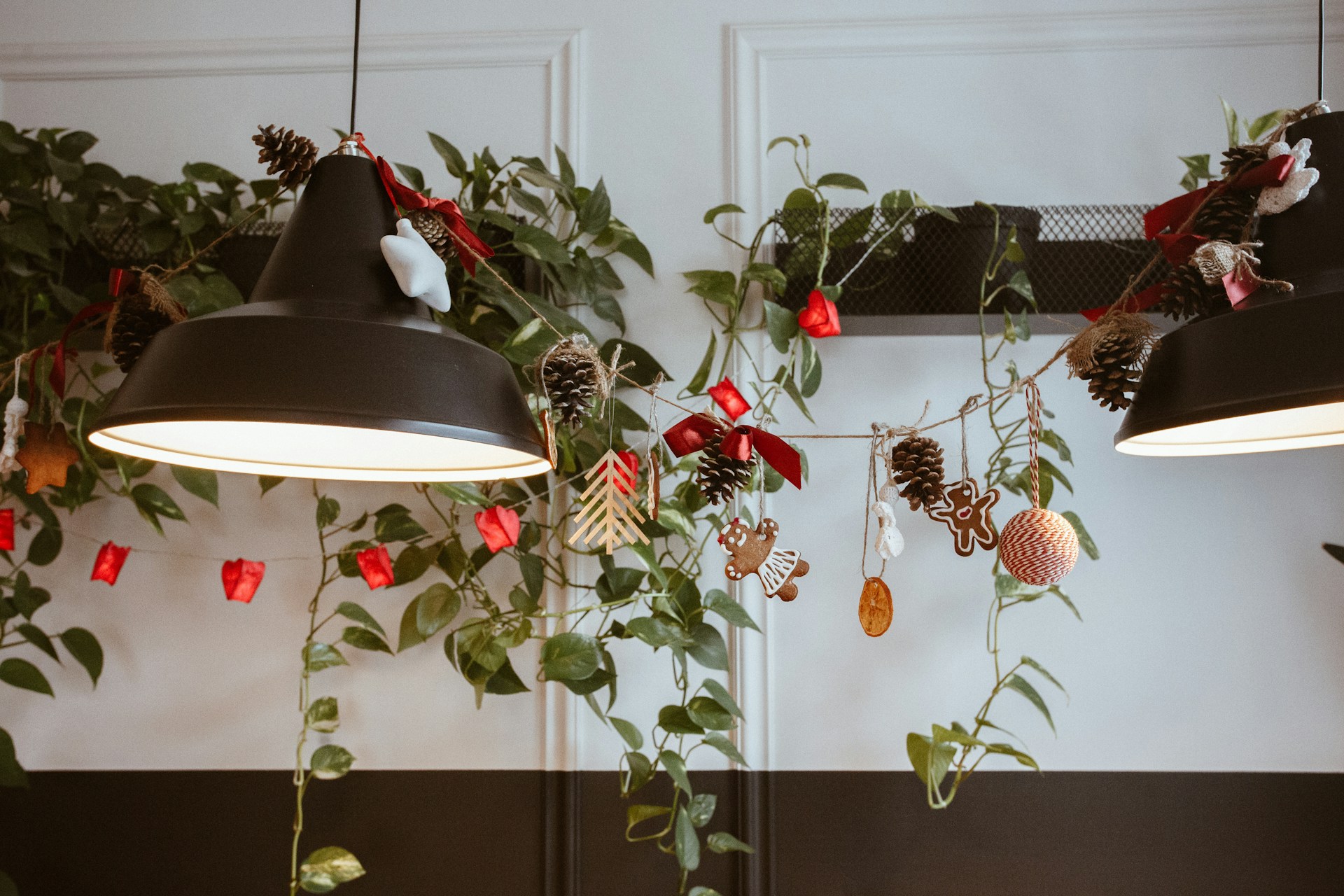 Black pendant lights with greenery, berries and ornaments draped between them