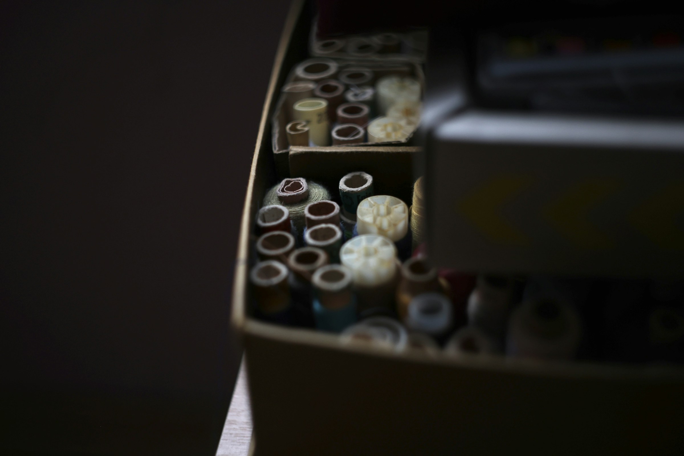 Wooden box filled with spools of sewing thread for a sewing circle