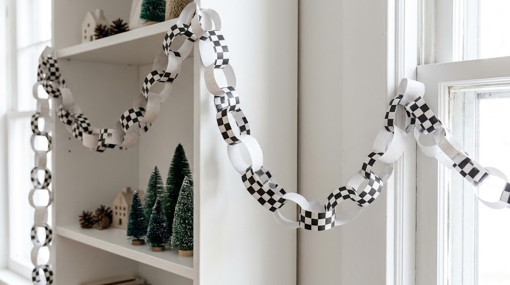 Black and white checkerboard paper chain garland draped across a white shelf and window