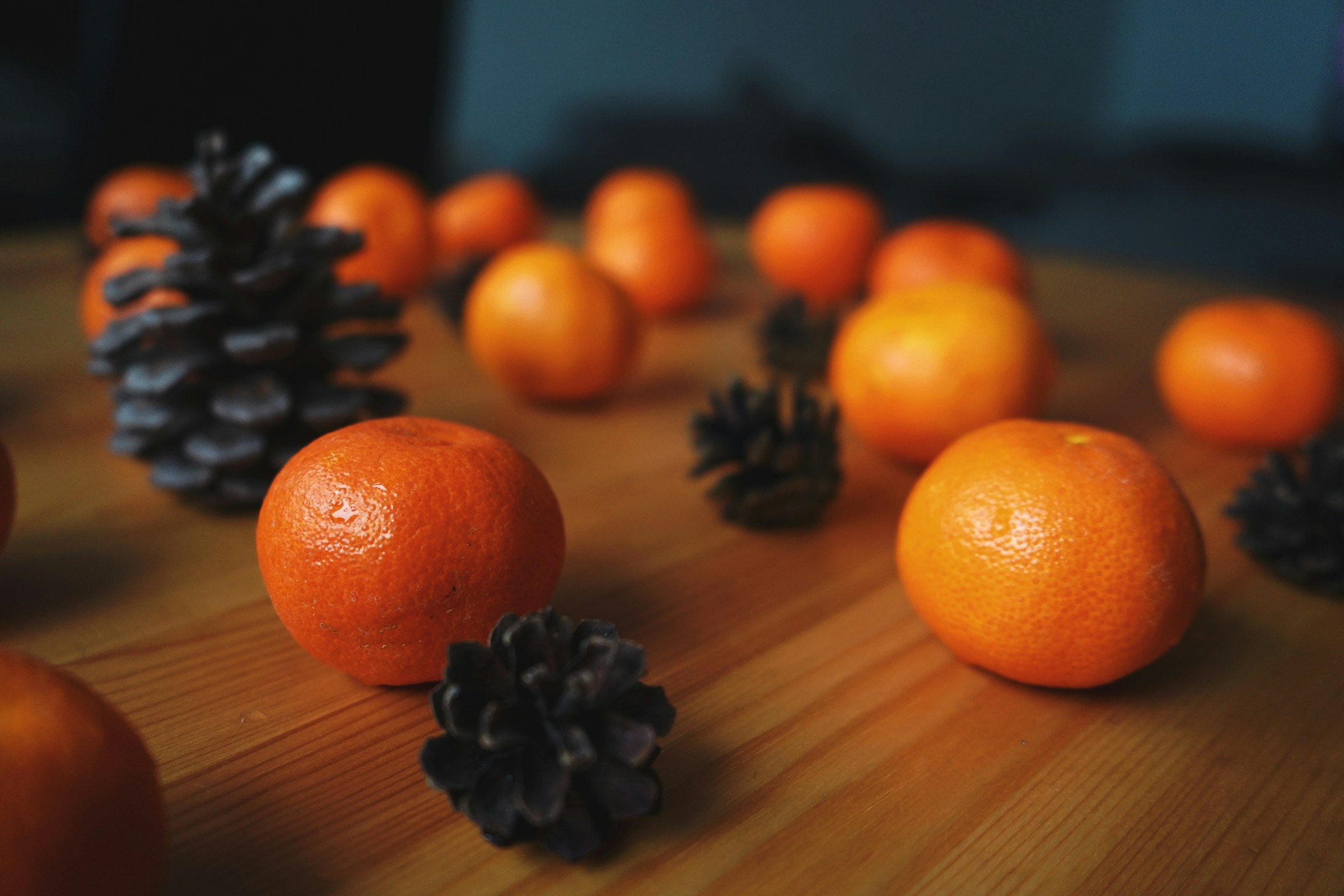 Clementines and pine cones scattered on a wooden table