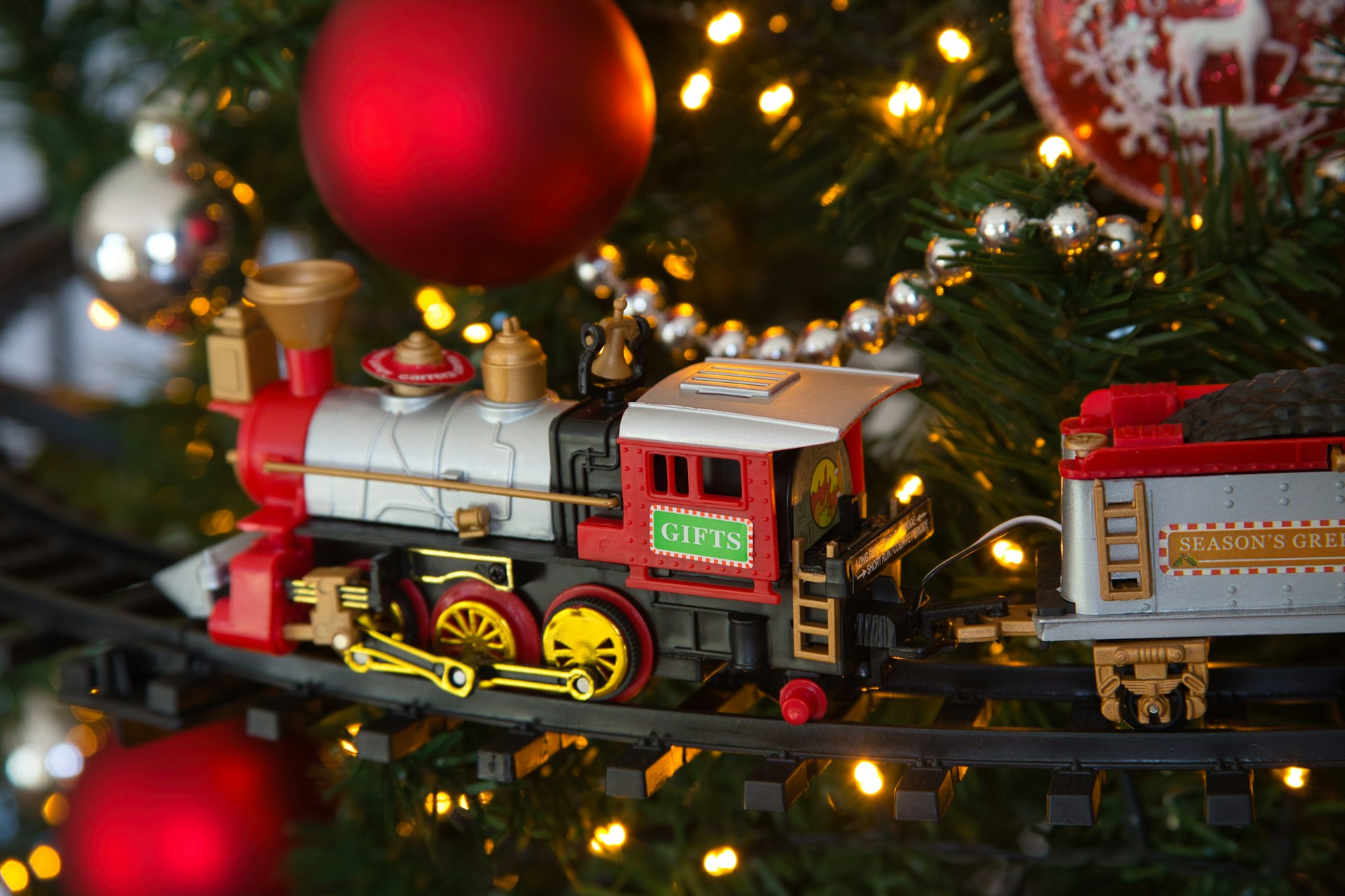 Christmas train decor with a toy train running through the branches of a lit tree