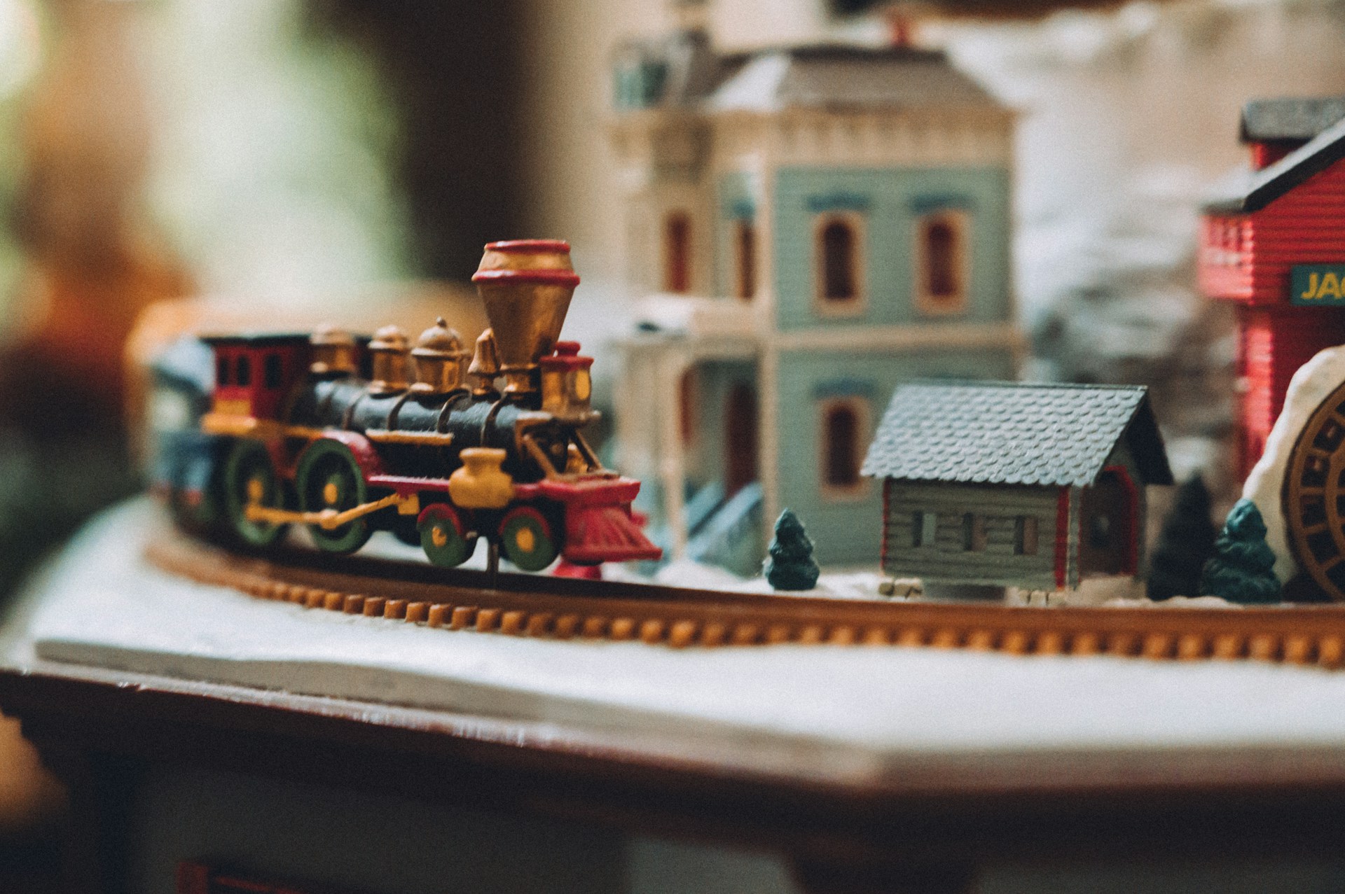Toy steam train passing small village houses on a snowy tabletop layout