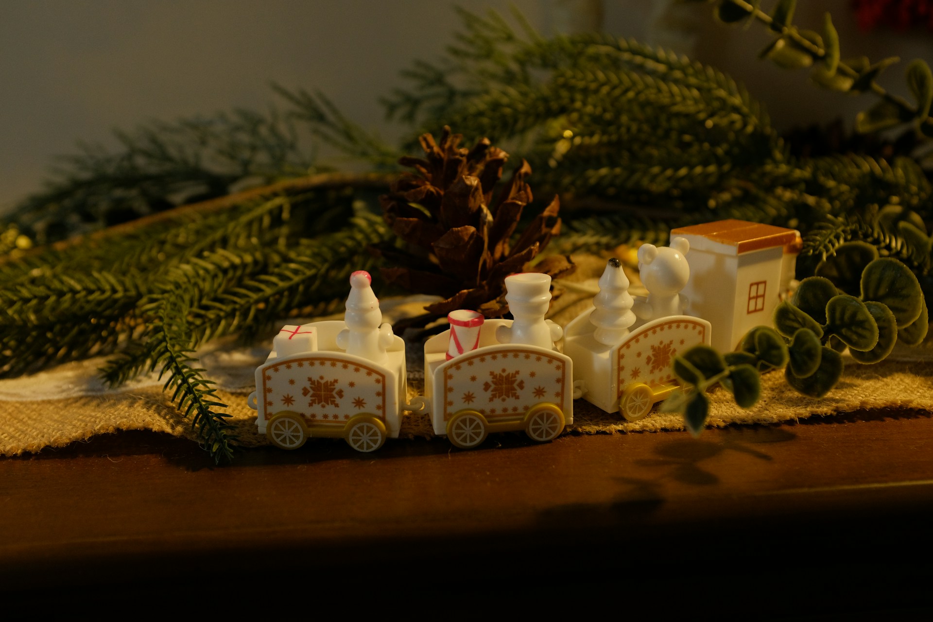 White painted wooden train with pine cones and greenery on a table