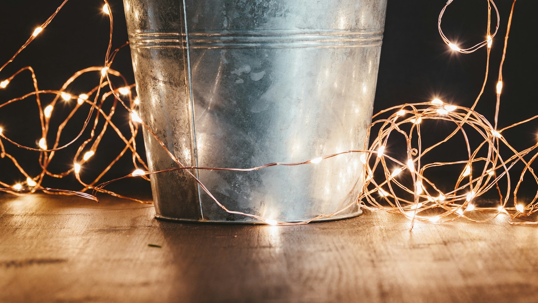 Small Christmas tree planted in a metal bucket with string lights