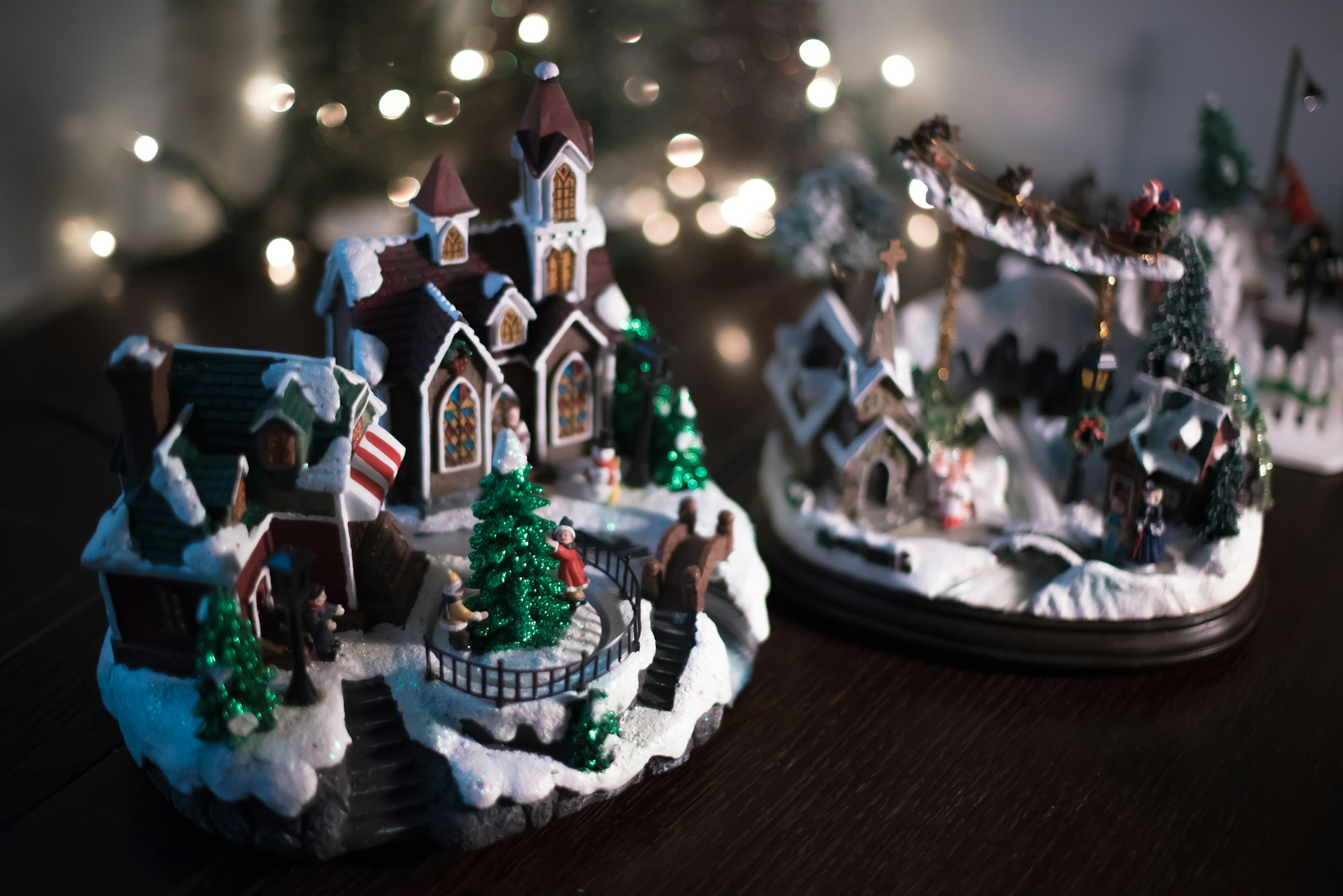 Christmas village display houses with tiny figures, a skating scene and snowy trees