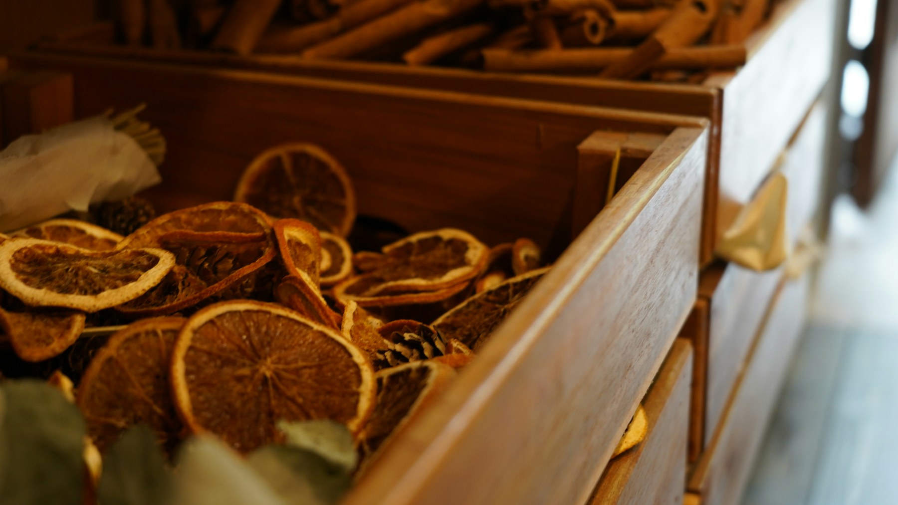 Dried orange slices and cinnamon sticks in wooden bins