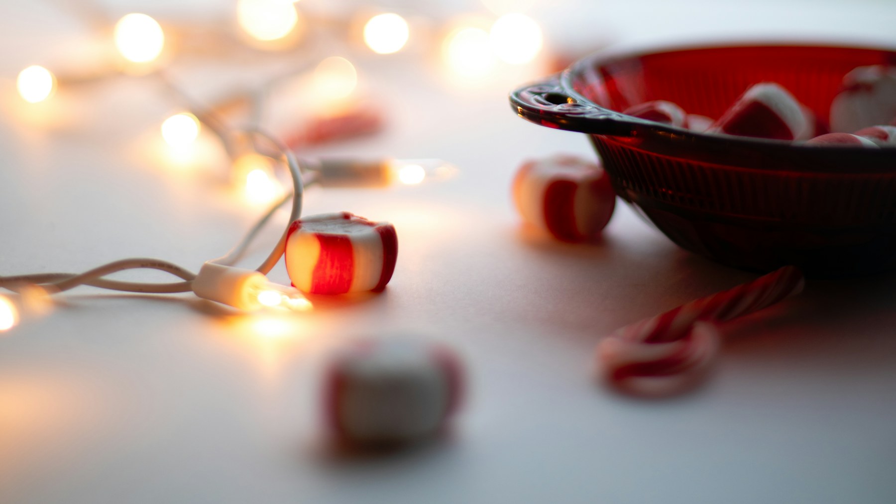 Red bowl of peppermint candies with string lights