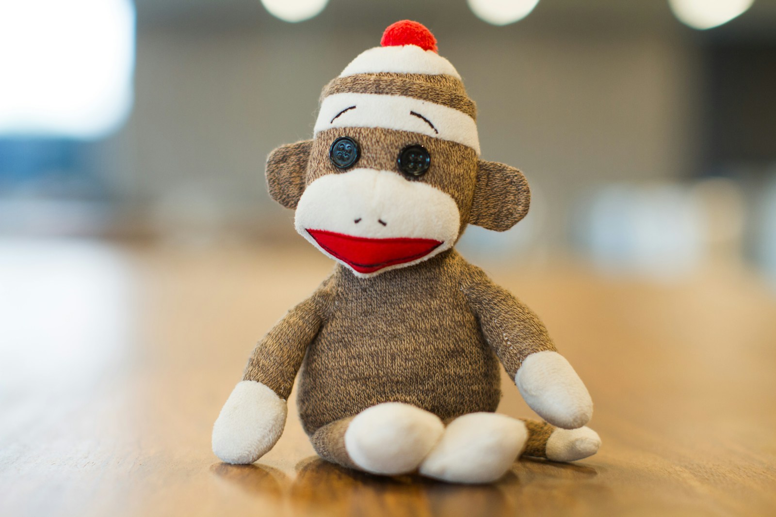 Classic brown sock monkey with a red mouth sitting on a wooden table