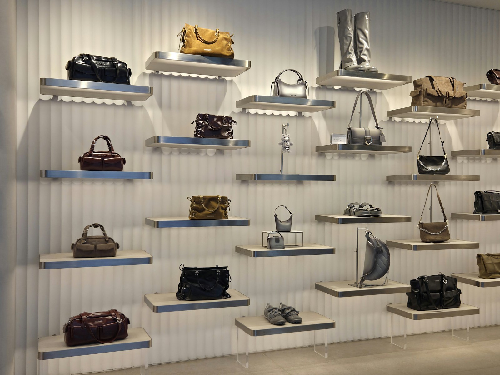 Handbags displayed on floating shelves on a white wall